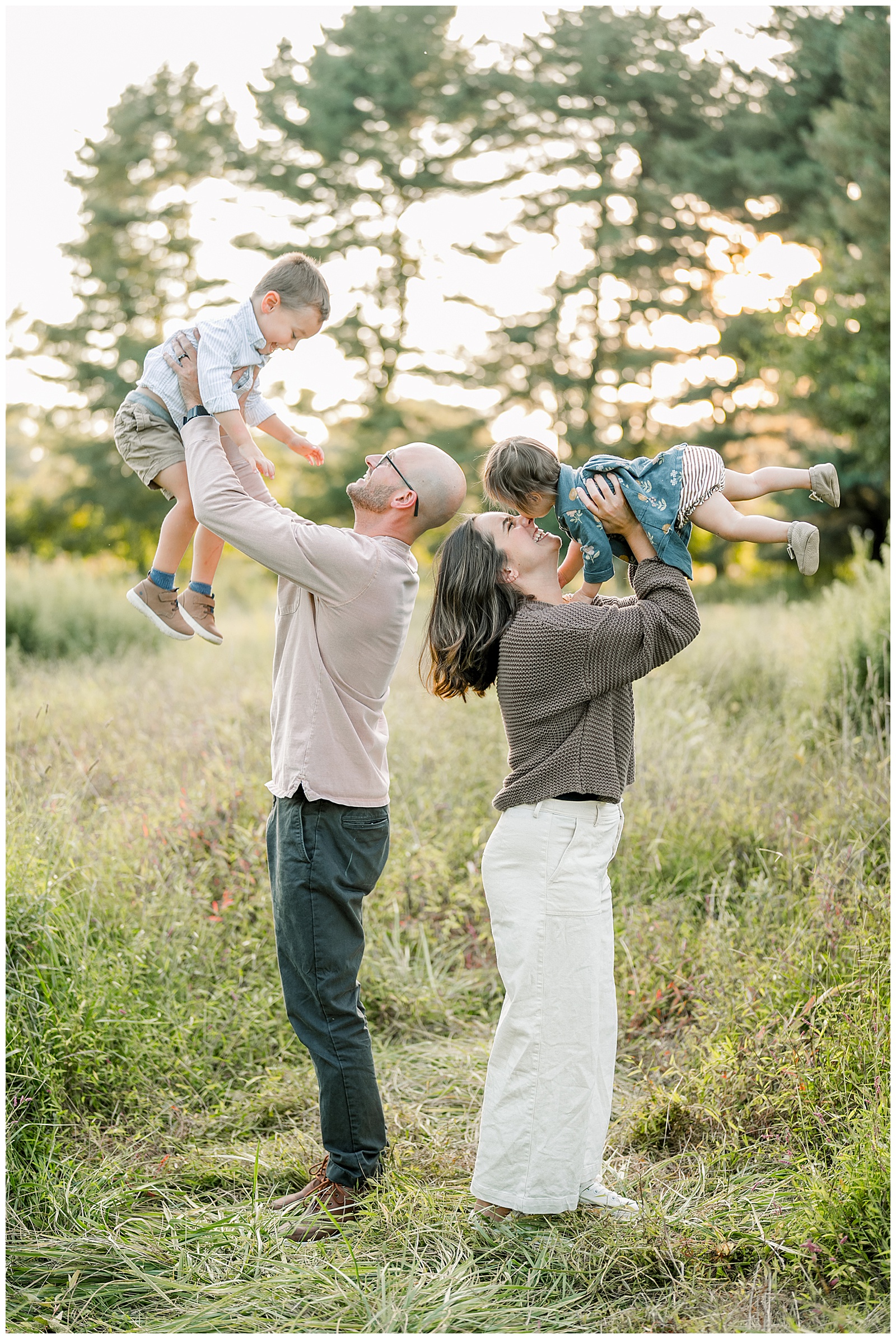parents raising their children up overhead in field at sunset for this Lancaster County Family Session