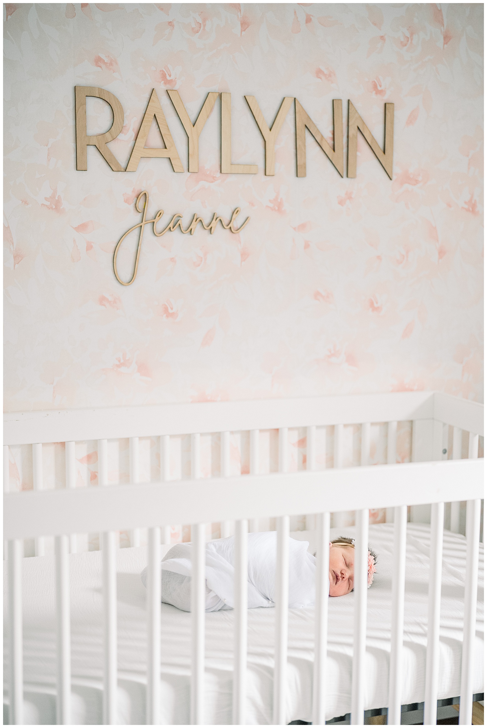 baby girl sleeping in her white crib with her name displayed on wall for this Neutral In-Home Newborn Session