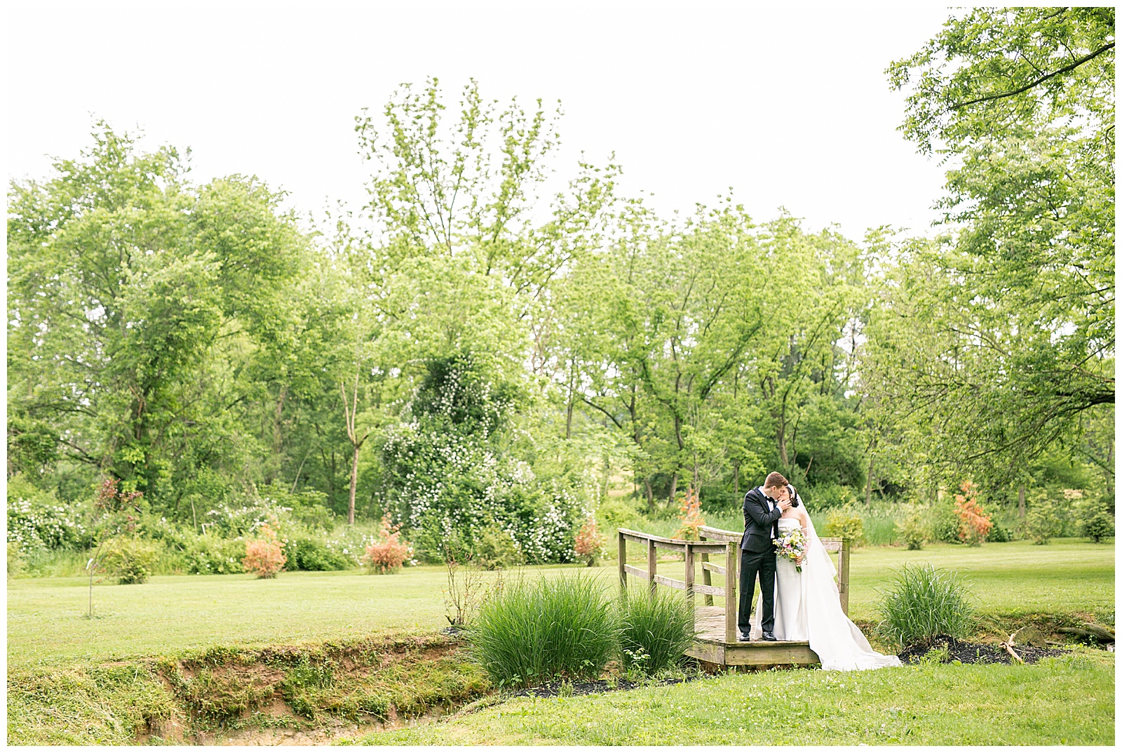couple standing on bridge and kissing for this Osbornia Farm Wedding